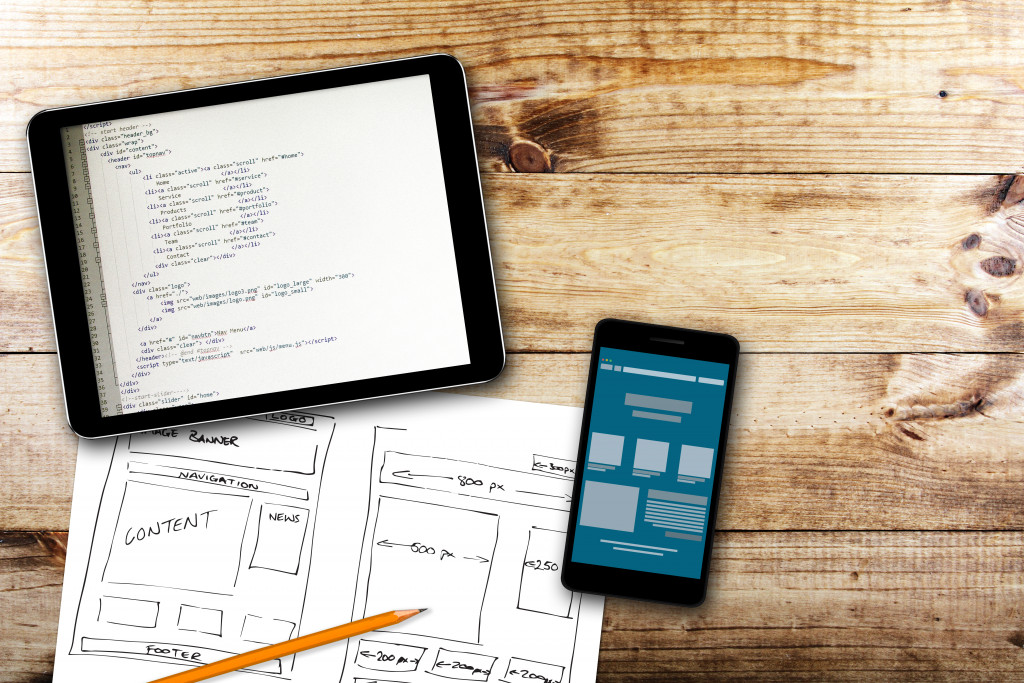 website wireframe sketch and programming code on digital tablet