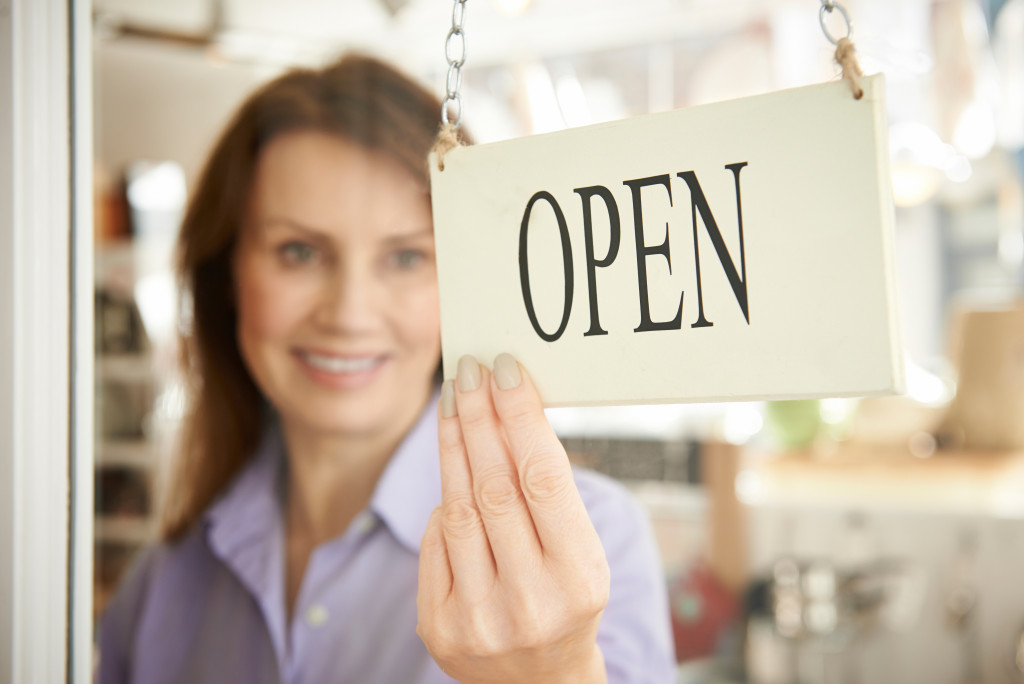 Store Owner Turning Open Sign In Shop Doorway