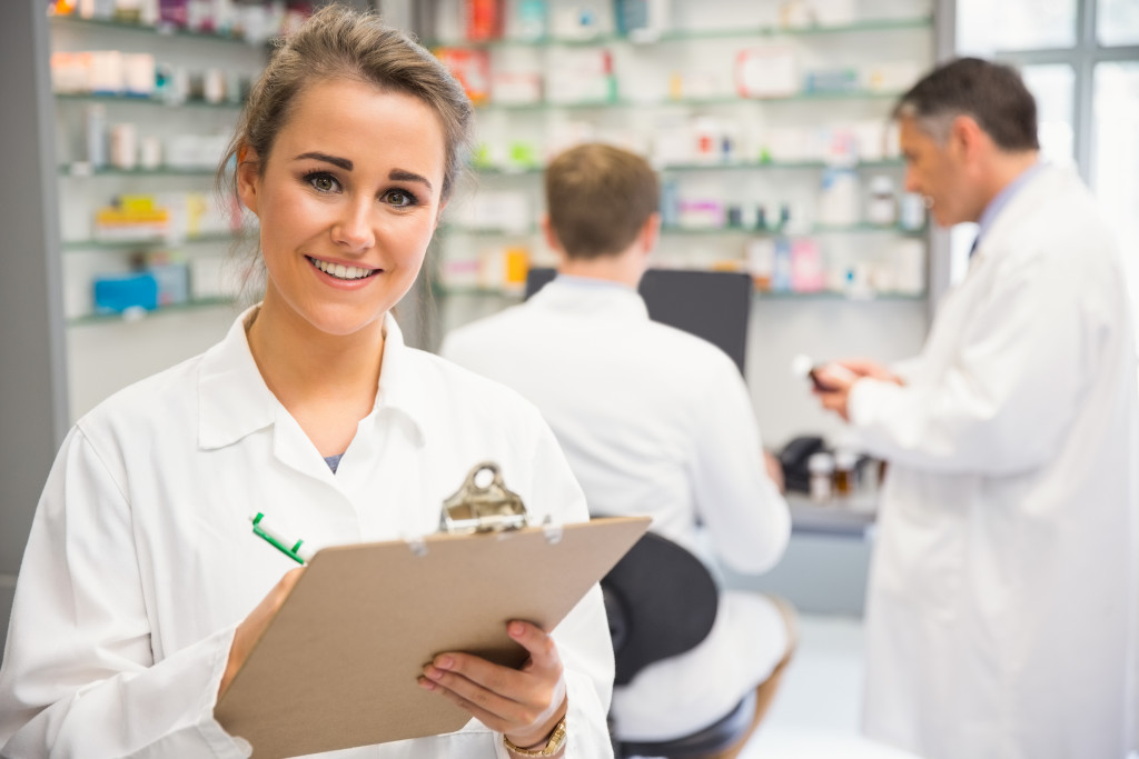 Junior pharmacist writing on clipboard at the hospital pharmacy