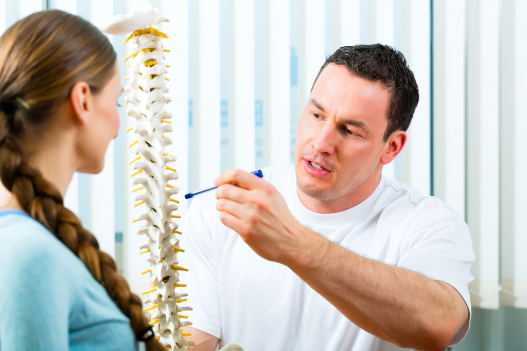a therapist showing patient a 3d model of spine