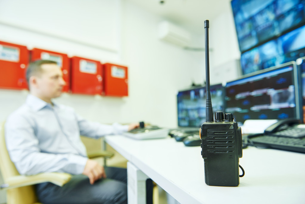 A two-way radio on a table of a security personnel watching surveillance monitors