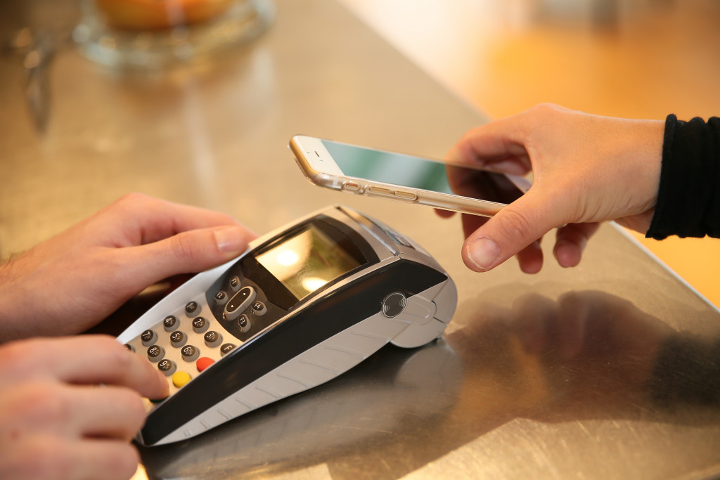a person holding phone near the transaction device