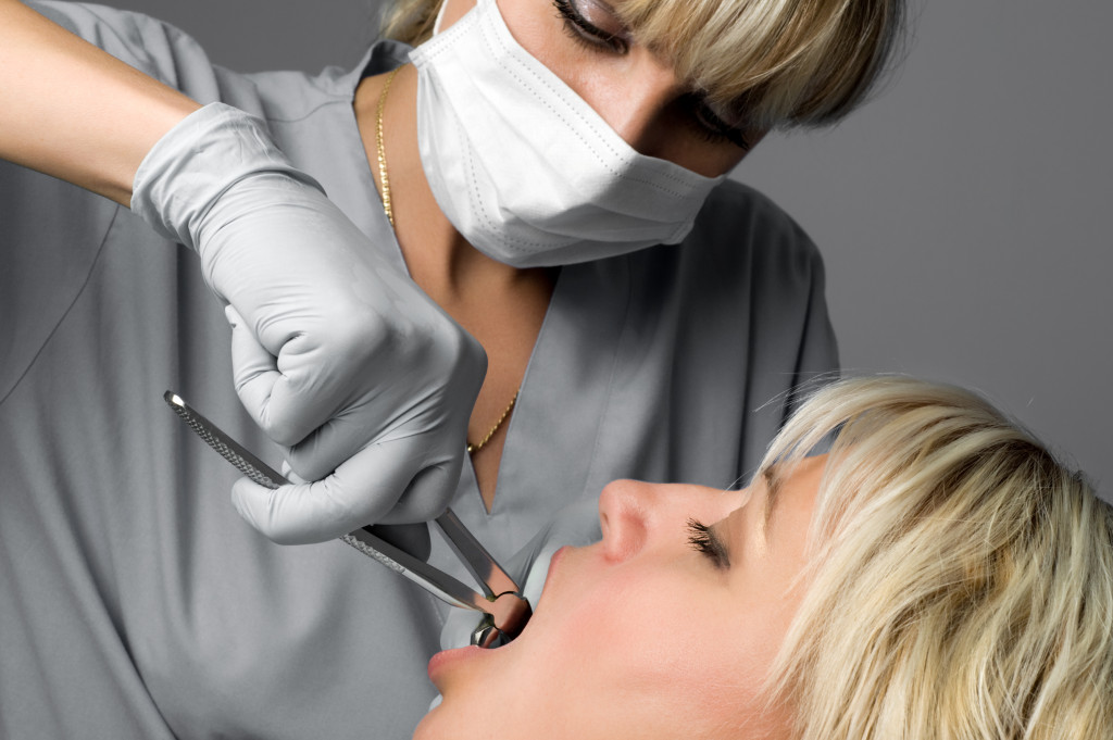 A dentist is doing a wisdom teeth removal procedure to a female patient.