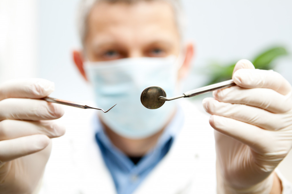 A dentist holding a dentistry hook and mirror