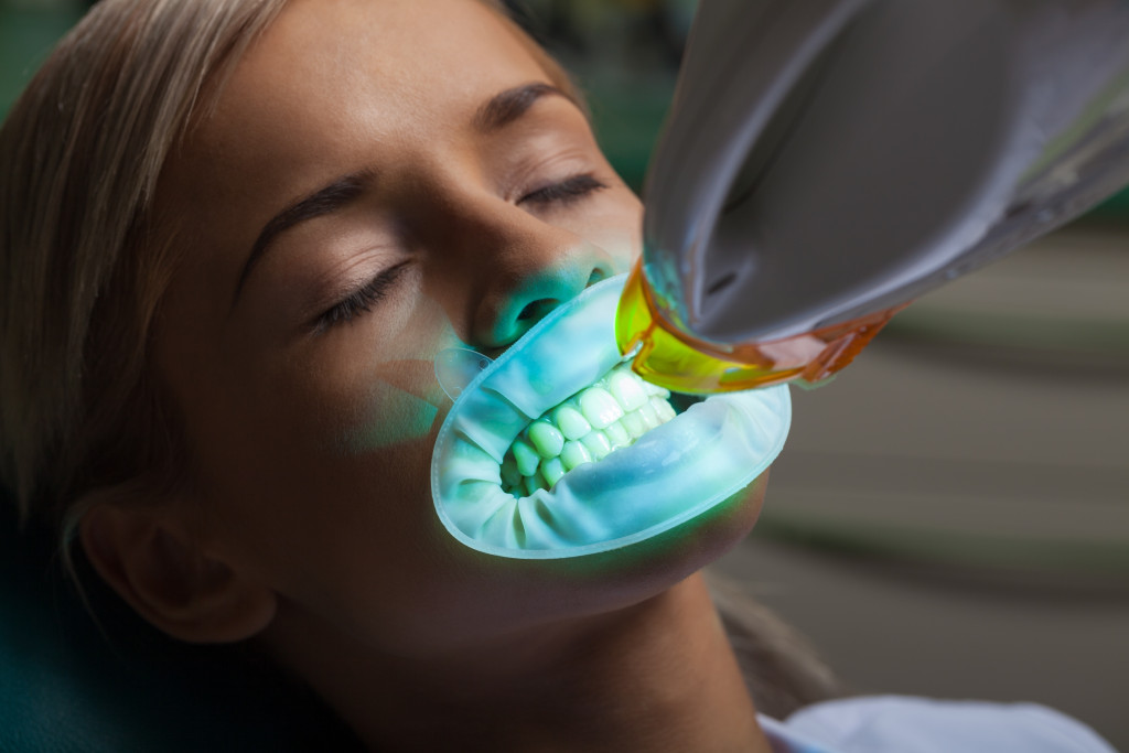 A woman getting a dental whitening treatment with a UV light on her teeth