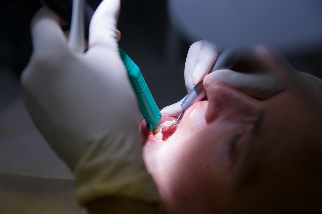 A dentist using tools to work on a patient's mouth with a spotlight on the work area