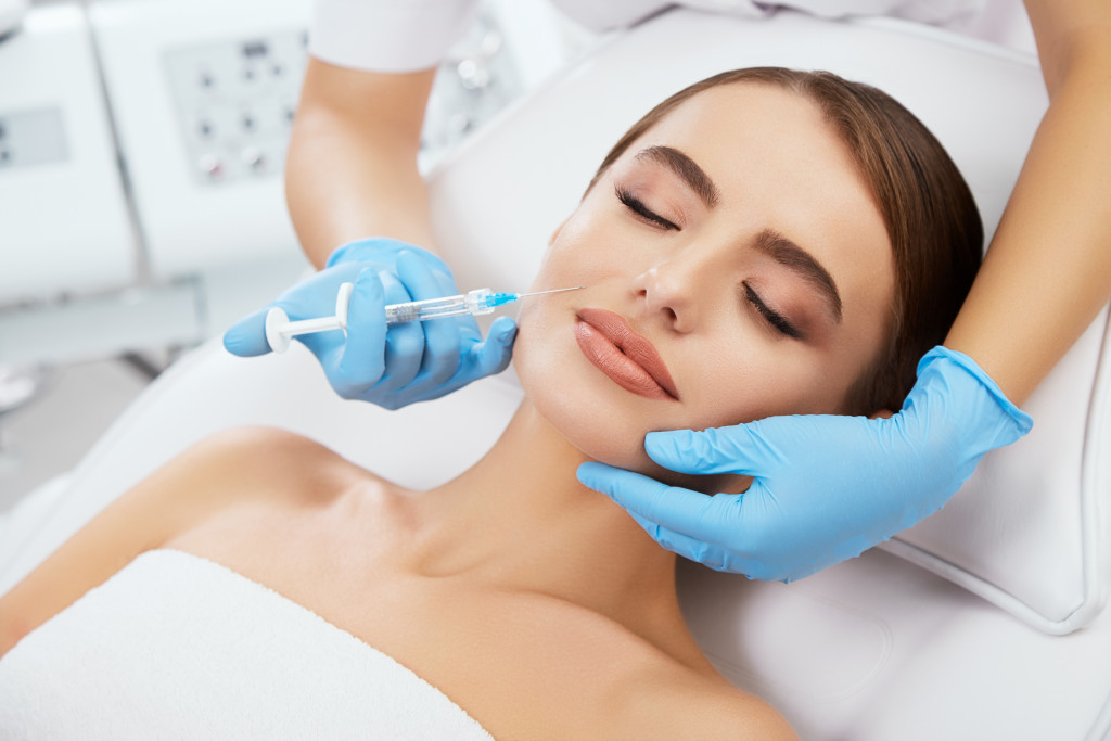a woman lying down in the clinic while receiving dermal fillers