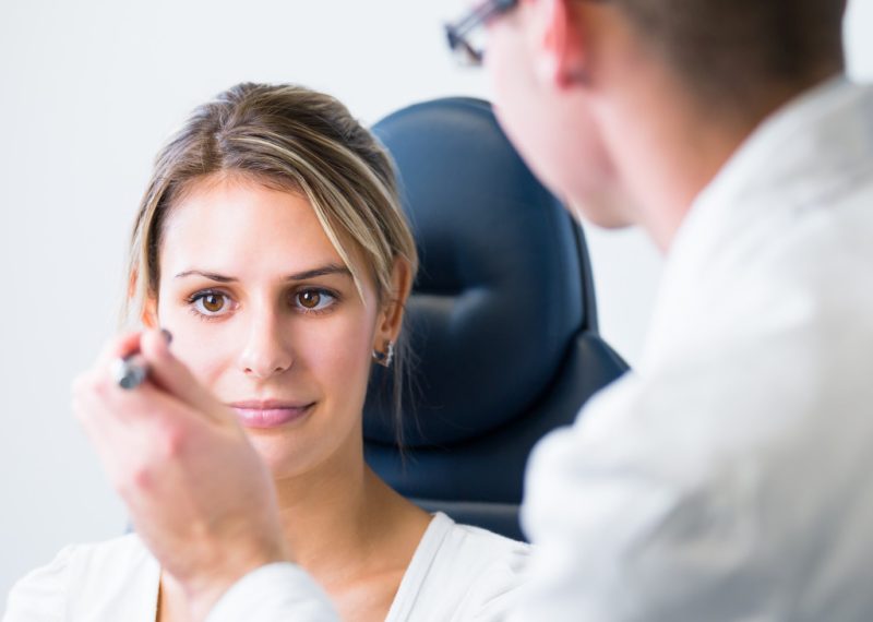 Pretty young woman having her eyes examined by an eye doctor