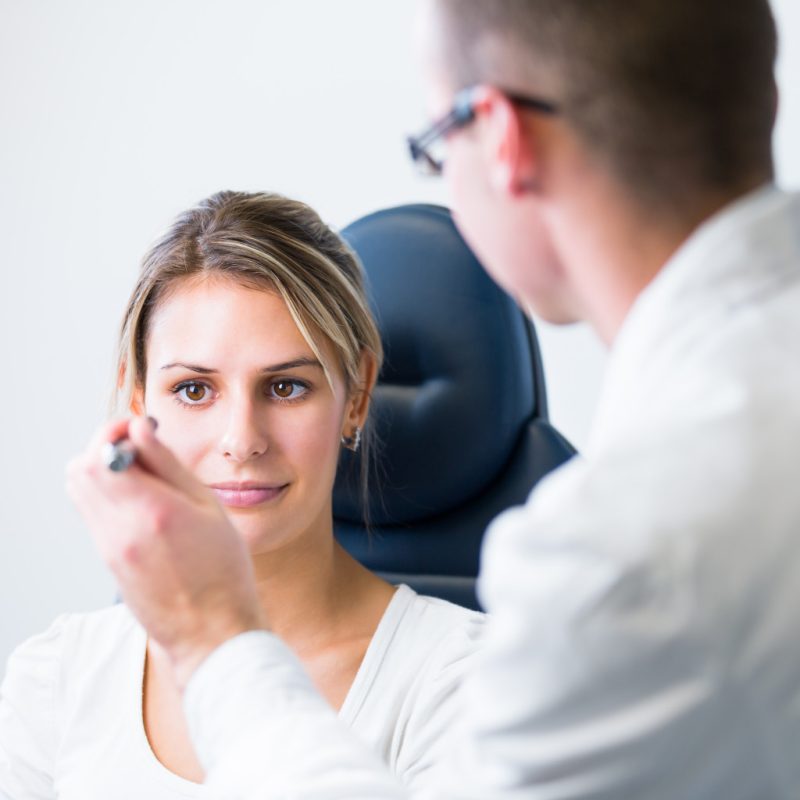 Pretty young woman having her eyes examined by an eye doctor