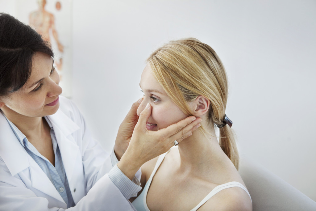 woman having her face massaged by a female medical personnel