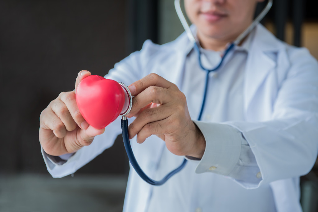 doctor putting a stethoscope on heart model concept of heart disease