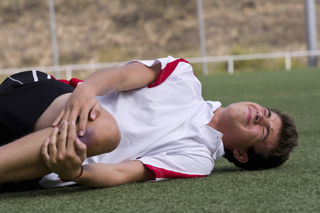 Football player holding his bruised knee after an injury on the field.