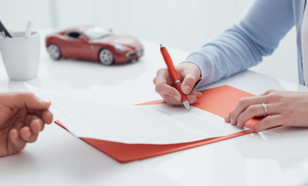 employee signing contract regarding the company car with red miniature car in the side
