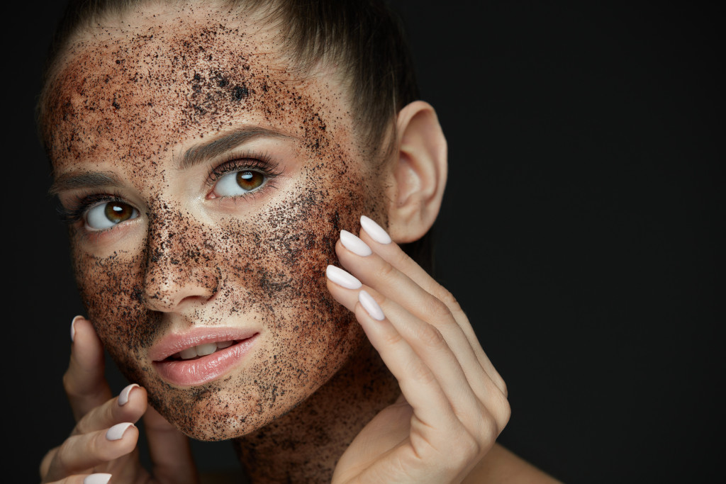 woman with dark facial scrub to exfoliate her face