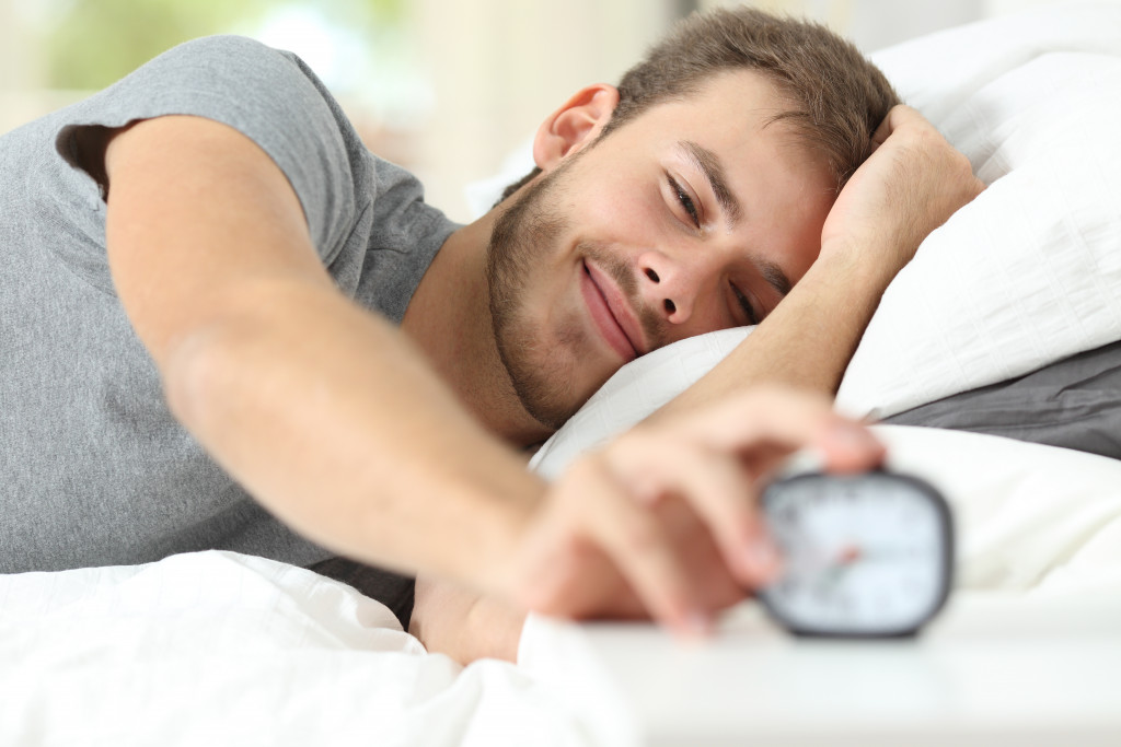 A man waking up and stopping his alarm clock