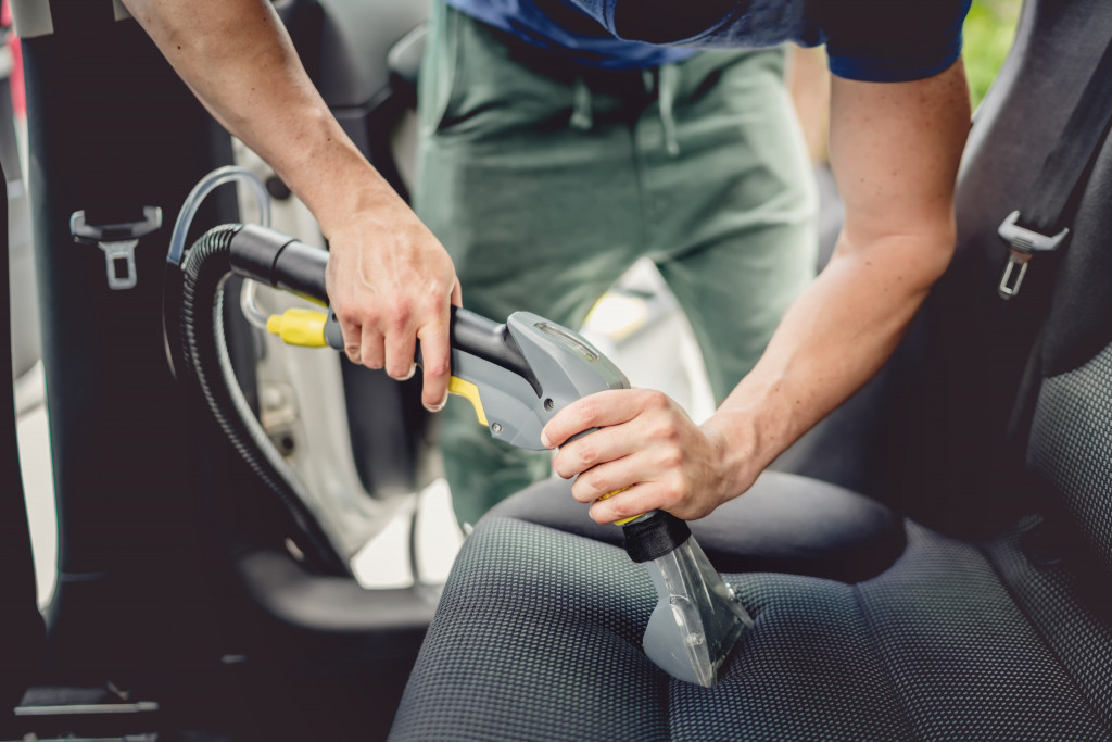 man vacuuming car seat